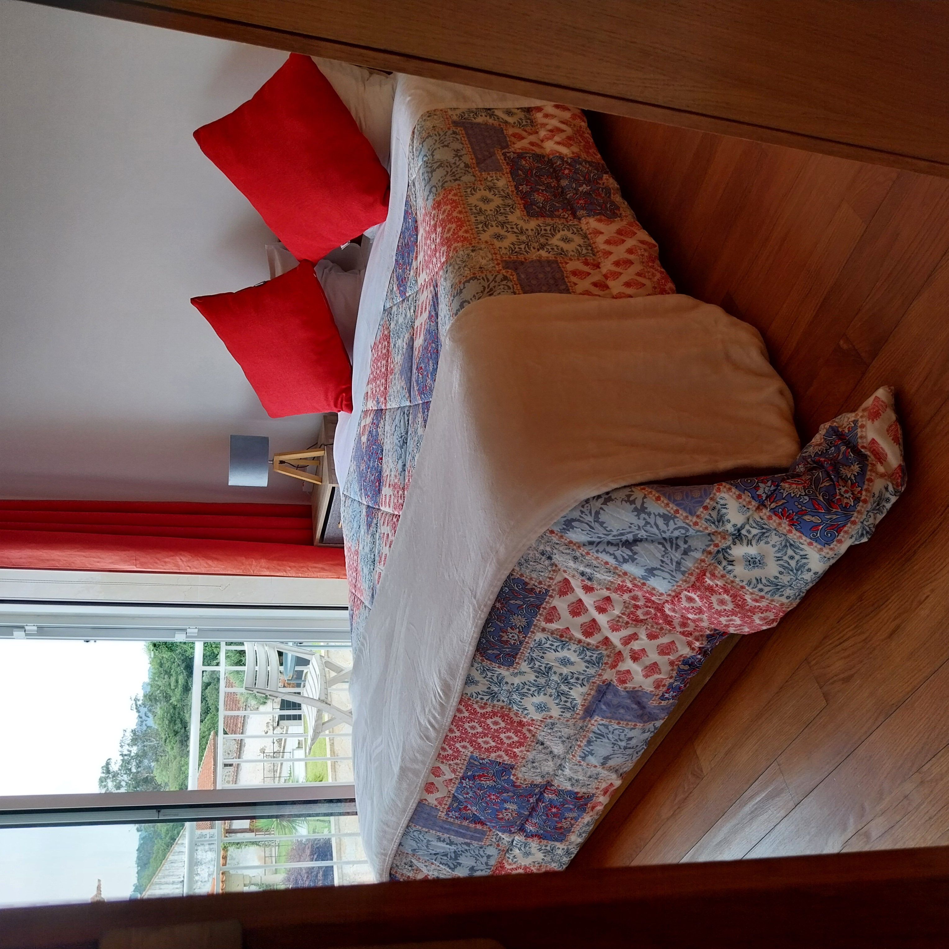 Cama de casal do Quarto Duplo com Varanda, com porta aberta para a varanda privativa e vista para a paisagem