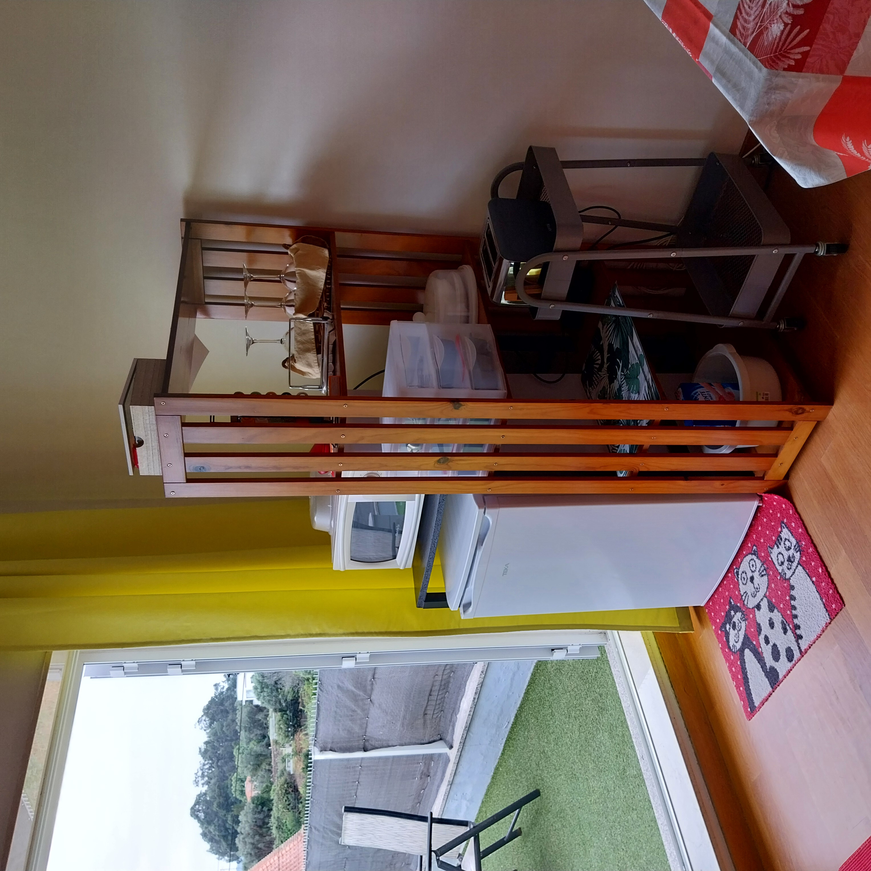 Sala de apoio com frigorífico, micro-ondas e utensílios junto à porta do terraço