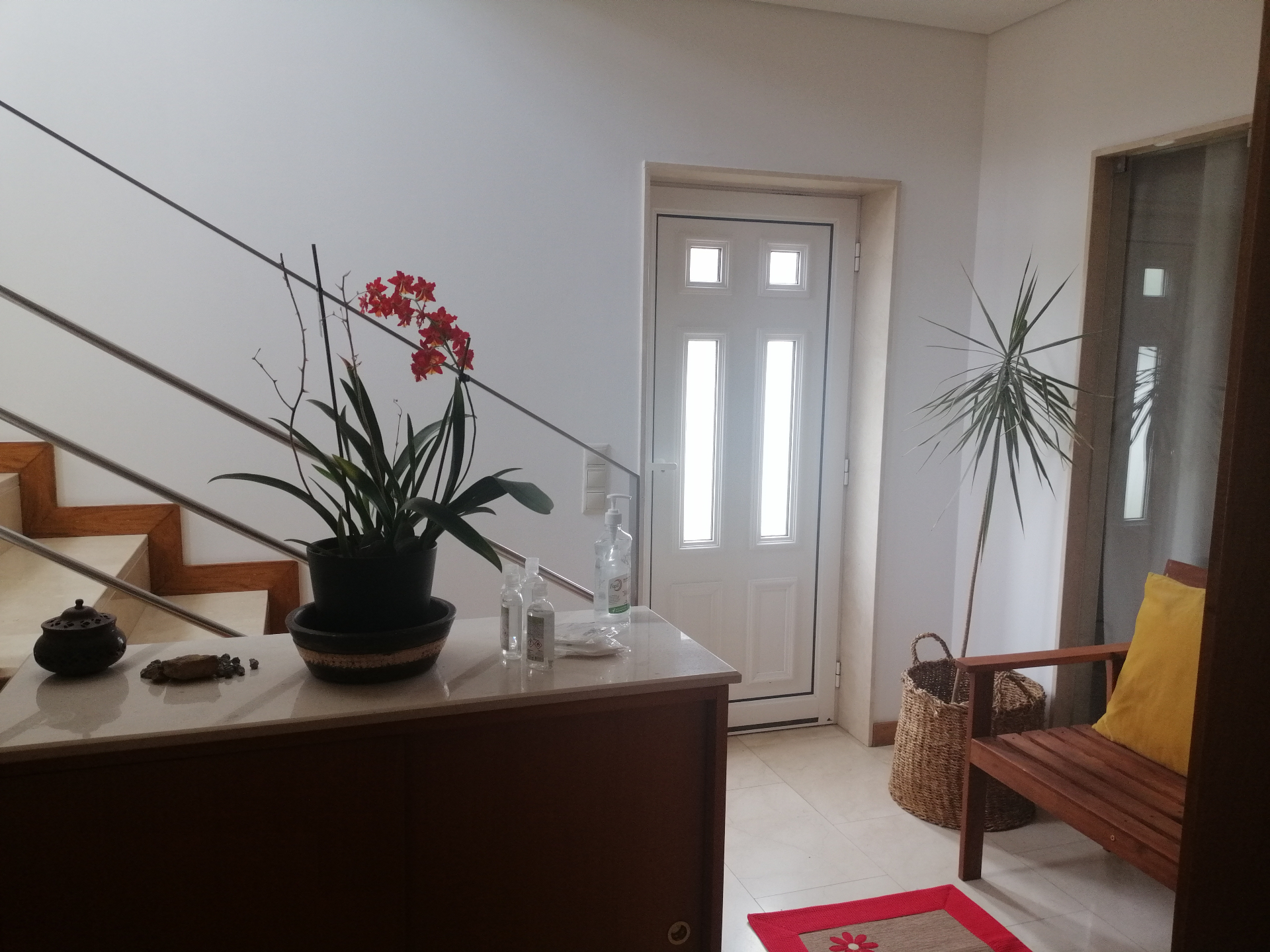 Hall de entrada do Portucellus House com porta branca, orquídea e escadaria de mármore